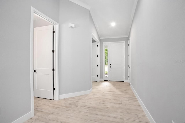 hall featuring ornamental molding, baseboards, and light wood finished floors