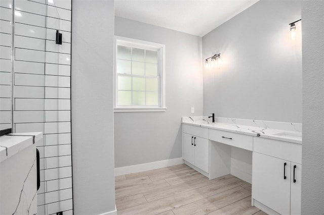 full bath with double vanity, wood finished floors, and baseboards