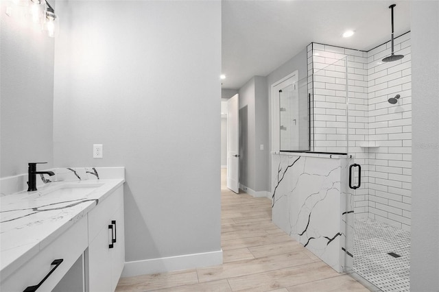 bathroom featuring a stall shower, vanity, baseboards, and wood finished floors