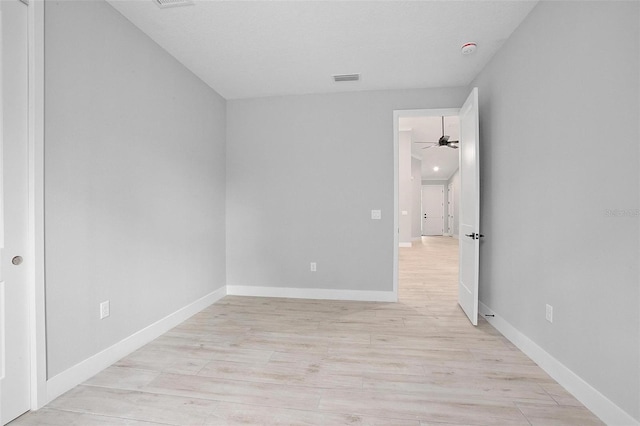 unfurnished room with light wood-type flooring, baseboards, visible vents, and a ceiling fan