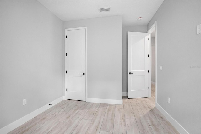 unfurnished bedroom featuring light wood finished floors, baseboards, and visible vents