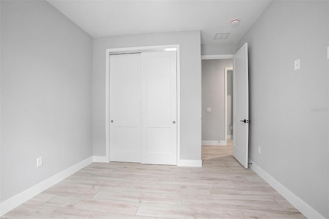 unfurnished bedroom featuring a closet, light wood-style flooring, and baseboards