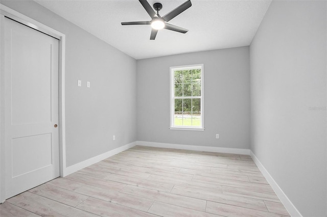 spare room featuring baseboards, ceiling fan, a textured ceiling, and light wood finished floors