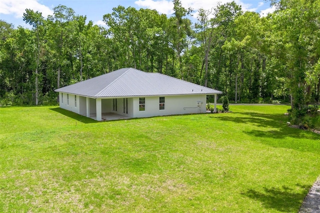 rear view of property with metal roof and a yard