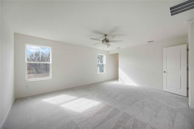 empty room with light carpet, a wealth of natural light, and ceiling fan