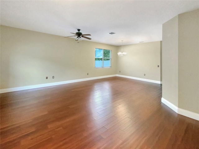 empty room with ceiling fan with notable chandelier and dark hardwood / wood-style flooring