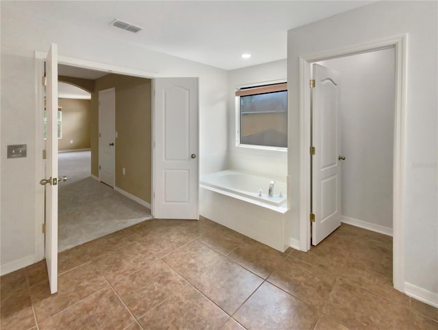 bathroom with tile floors and a bath to relax in