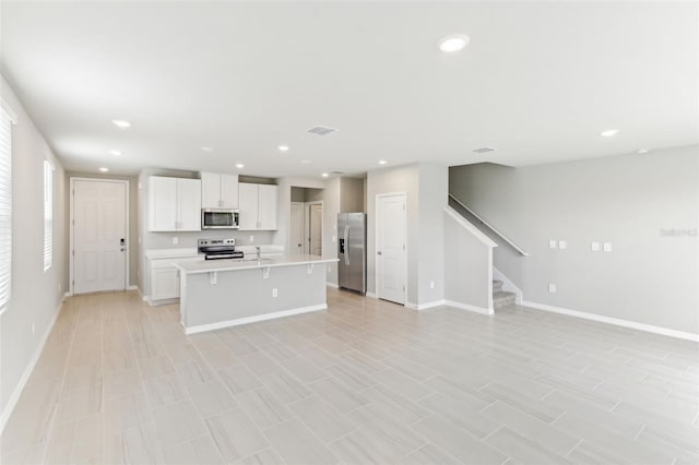 kitchen featuring white cabinets, a kitchen breakfast bar, an island with sink, light tile patterned flooring, and stainless steel appliances