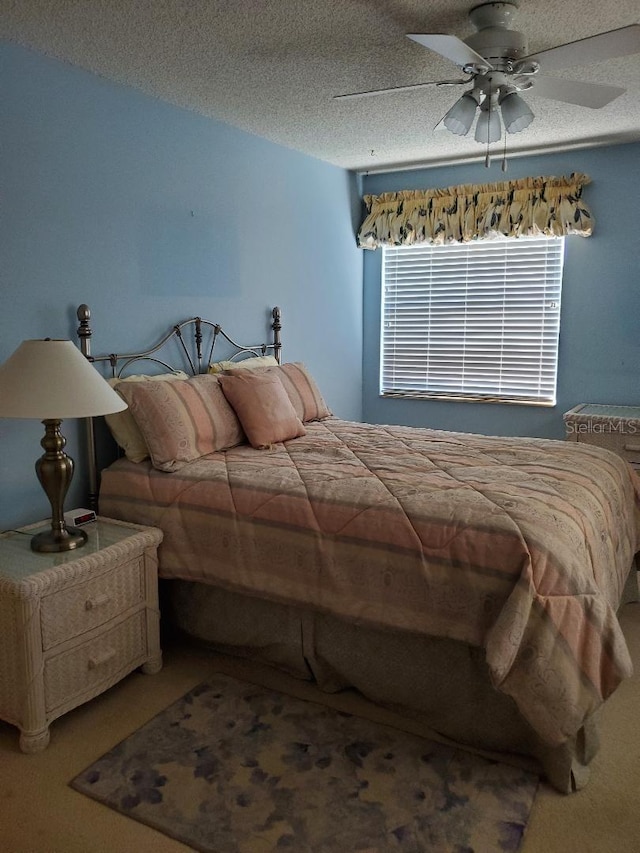 carpeted bedroom featuring ceiling fan and a textured ceiling