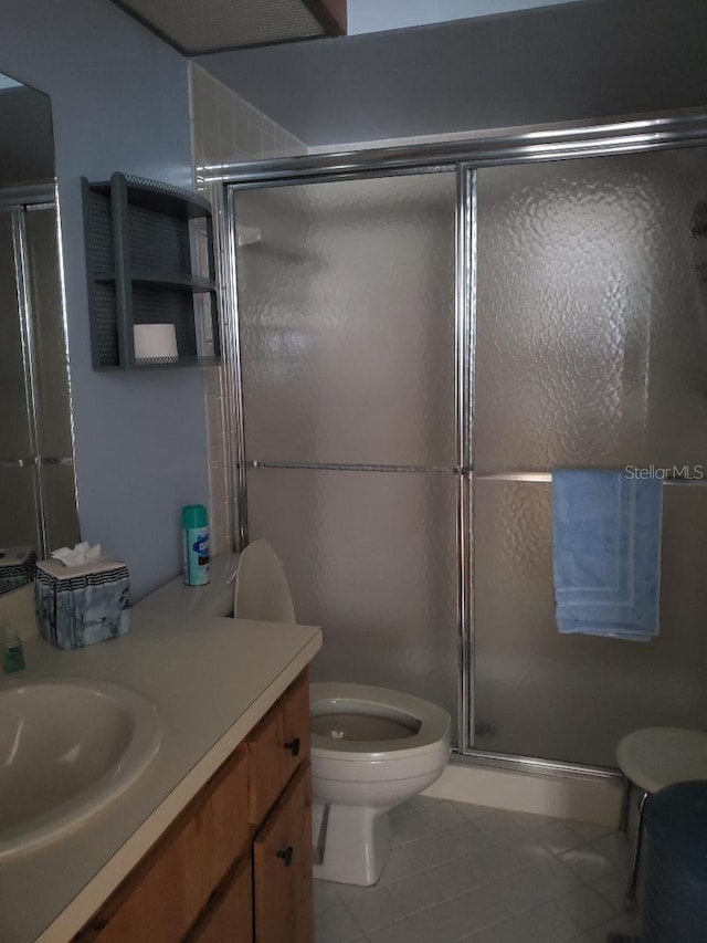 bathroom featuring toilet, an enclosed shower, tile patterned floors, and vanity