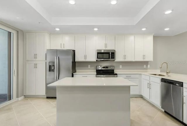 kitchen featuring sink, white cabinetry, stainless steel appliances, and a tray ceiling