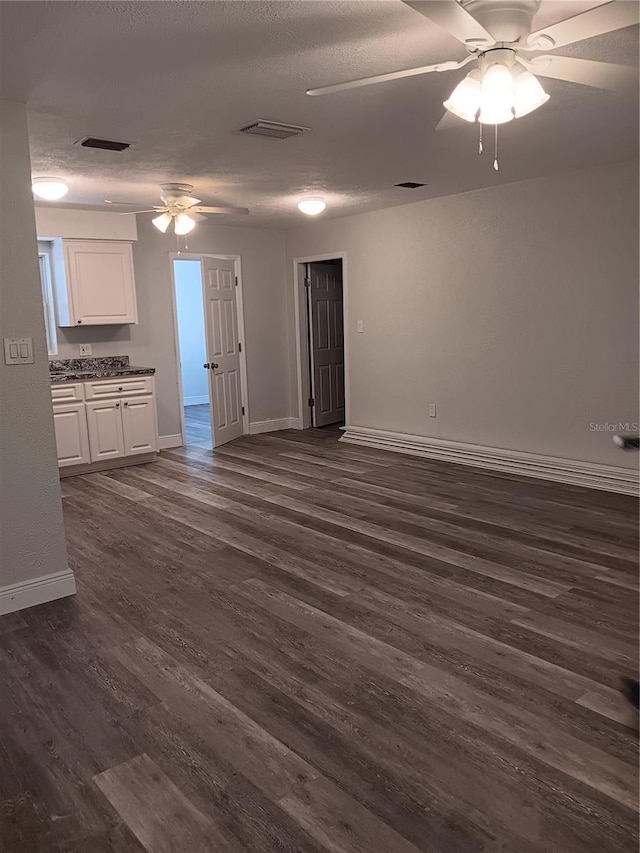 unfurnished living room with dark wood-type flooring, ceiling fan, and a textured ceiling