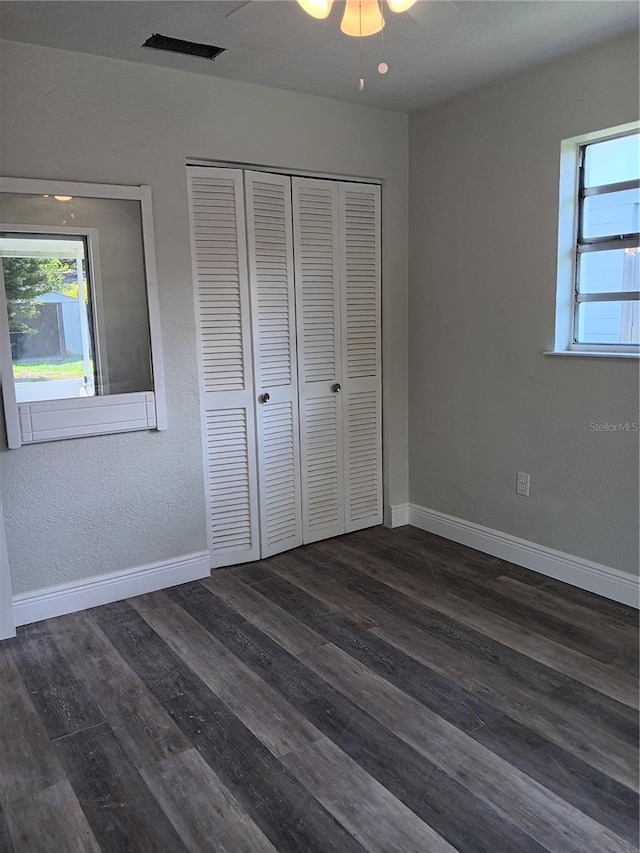 unfurnished bedroom with dark hardwood / wood-style flooring, a closet, and ceiling fan