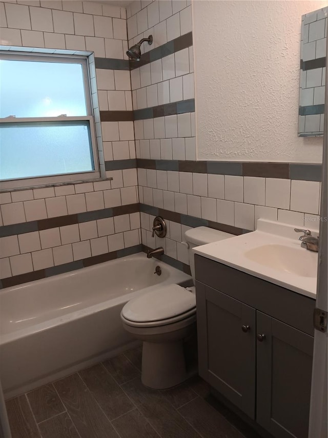 full bathroom with vanity, toilet, tile walls, and tiled shower / bath