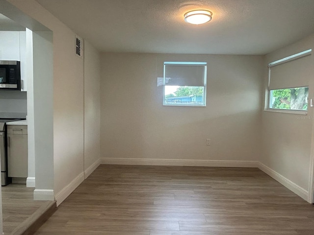 unfurnished room with a textured ceiling and light wood-type flooring