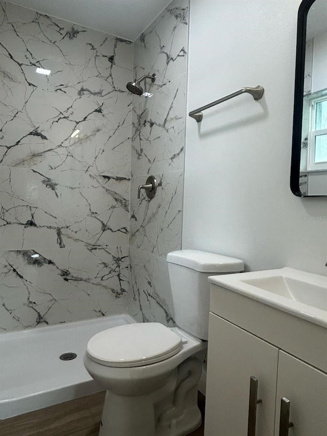 bathroom featuring tiled shower, hardwood / wood-style floors, vanity, and toilet