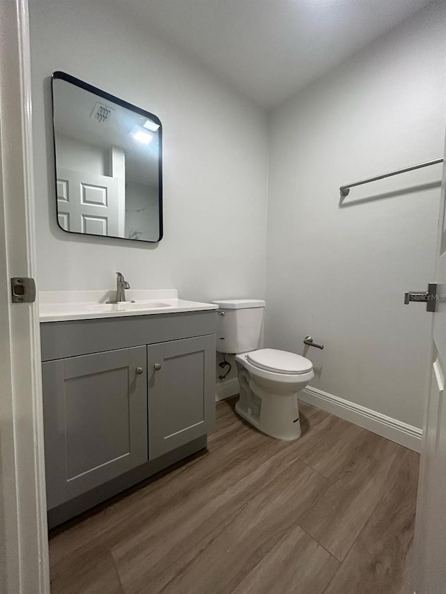 bathroom with hardwood / wood-style floors, vanity, and toilet