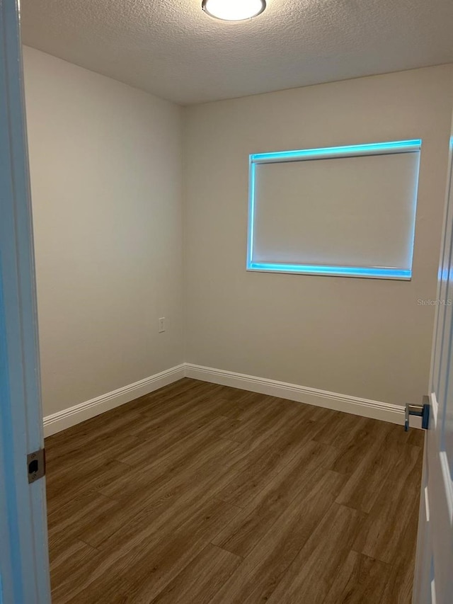 empty room with a textured ceiling and dark wood-type flooring