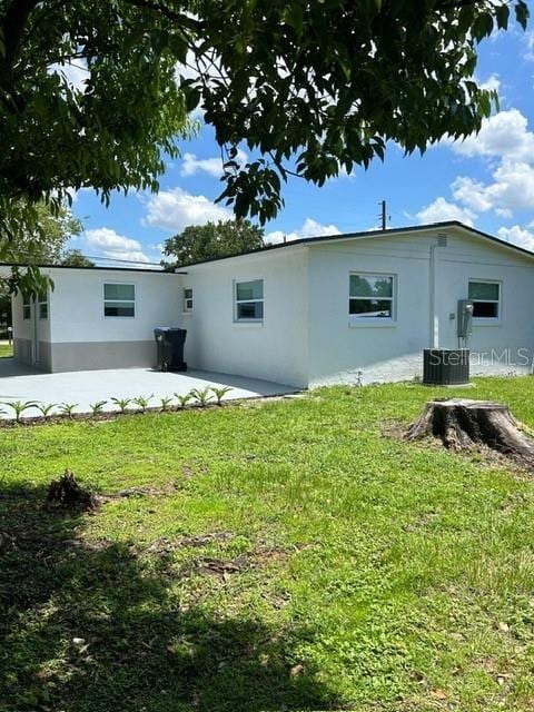 back of property with central air condition unit, a patio area, and a yard