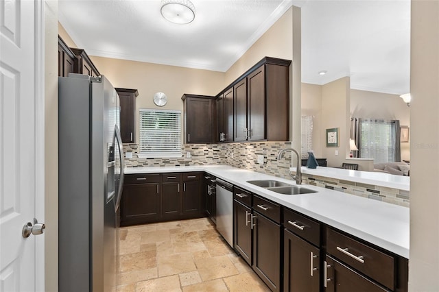 kitchen with sink, stainless steel appliances, decorative backsplash, dark brown cabinets, and ornamental molding