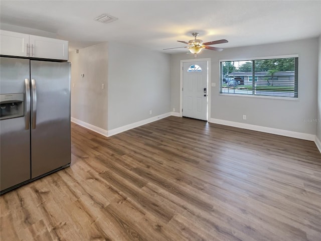 interior space with stainless steel fridge, white cabinets, wood-type flooring, and ceiling fan