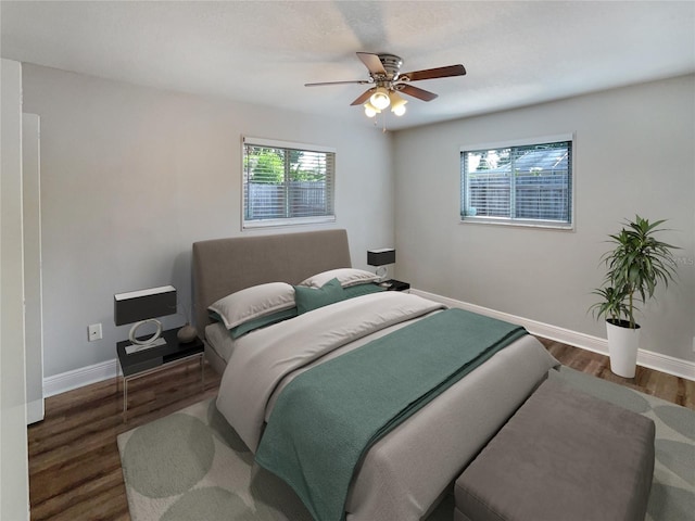 bedroom featuring ceiling fan, multiple windows, and dark hardwood / wood-style floors