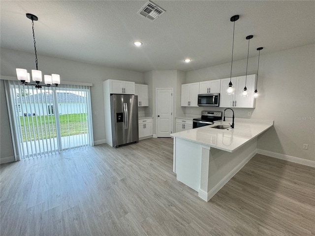 kitchen with light hardwood / wood-style floors, kitchen peninsula, pendant lighting, and appliances with stainless steel finishes