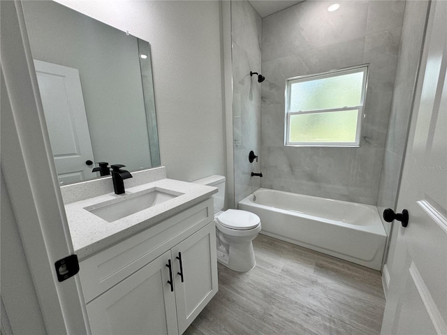 full bathroom with tiled shower / bath, hardwood / wood-style floors, oversized vanity, and toilet