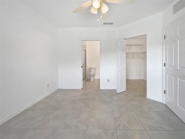 unfurnished bedroom with ensuite bathroom, ceiling fan, a spacious closet, light tile patterned floors, and a closet