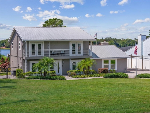 view of front facade featuring central AC unit, a balcony, french doors, and a front lawn