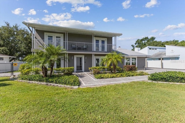 view of front of home with a balcony, french doors, and a front yard