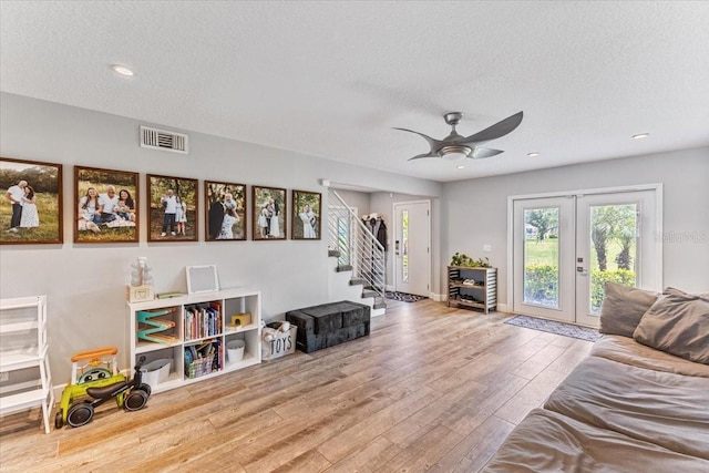 interior space with a textured ceiling, ceiling fan, light hardwood / wood-style flooring, and french doors