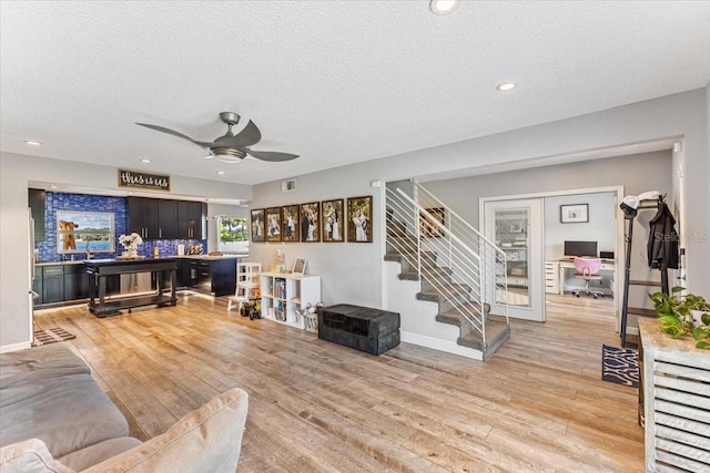 living room featuring light wood-type flooring, french doors, a textured ceiling, and ceiling fan