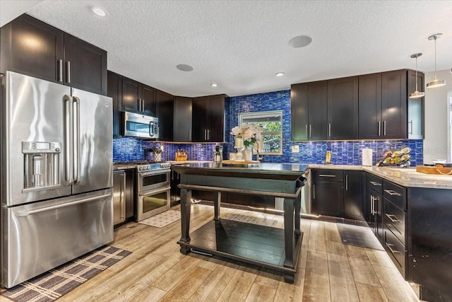 kitchen featuring pendant lighting, premium appliances, light hardwood / wood-style floors, and backsplash