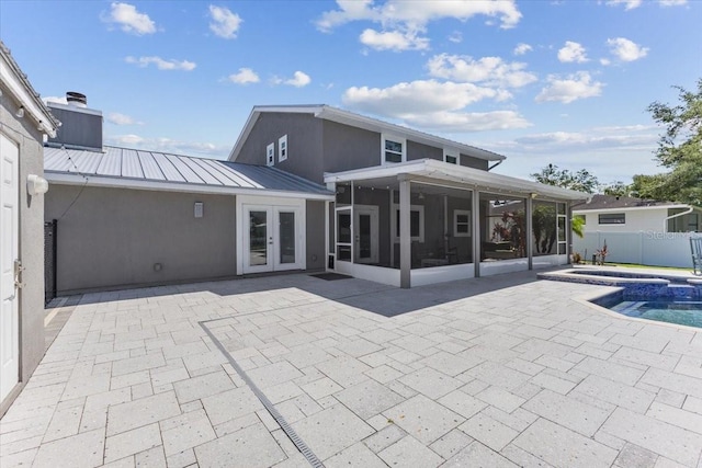 back of property featuring a sunroom, french doors, a patio, and a pool with hot tub