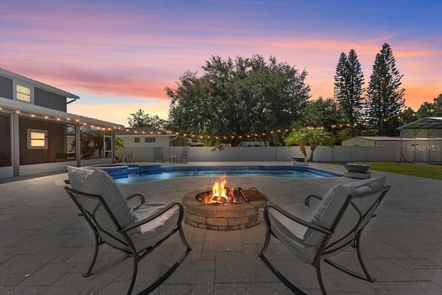 pool at dusk featuring a fire pit and a patio area