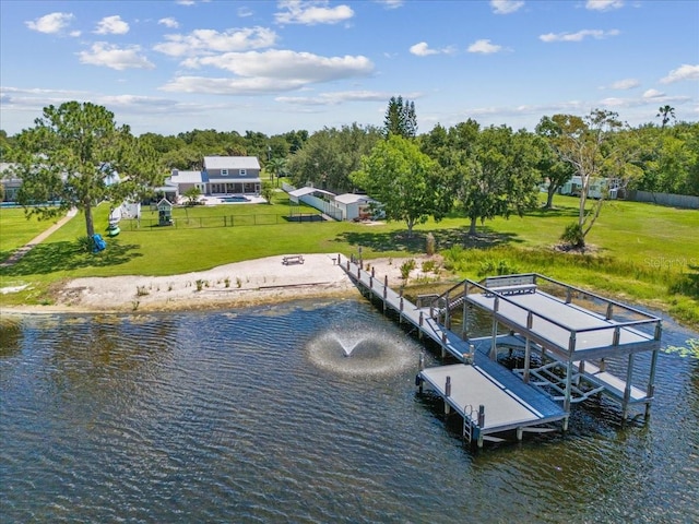 view of dock with a lawn and a water view