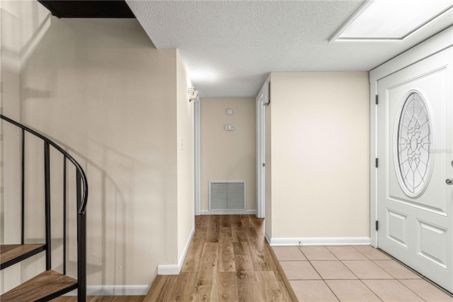 foyer with light wood-type flooring and a textured ceiling