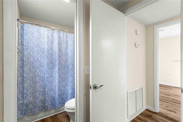 bathroom with toilet, a textured ceiling, and hardwood / wood-style flooring