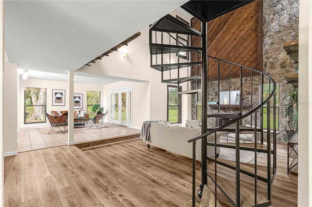 staircase with hardwood / wood-style floors, a textured ceiling, and a towering ceiling