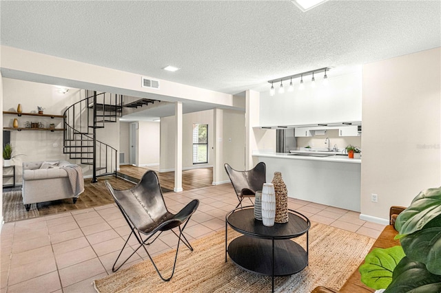 living room with light tile patterned floors, sink, and a textured ceiling