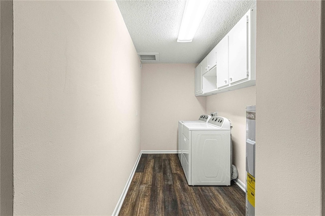 clothes washing area featuring dark wood-type flooring, separate washer and dryer, a textured ceiling, and cabinets