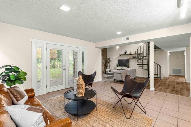 tiled living room featuring french doors and a textured ceiling