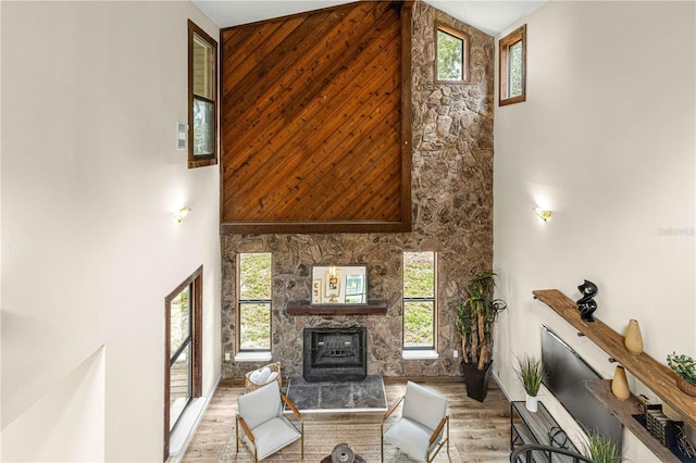 living room with hardwood / wood-style flooring, wooden walls, a towering ceiling, and a fireplace