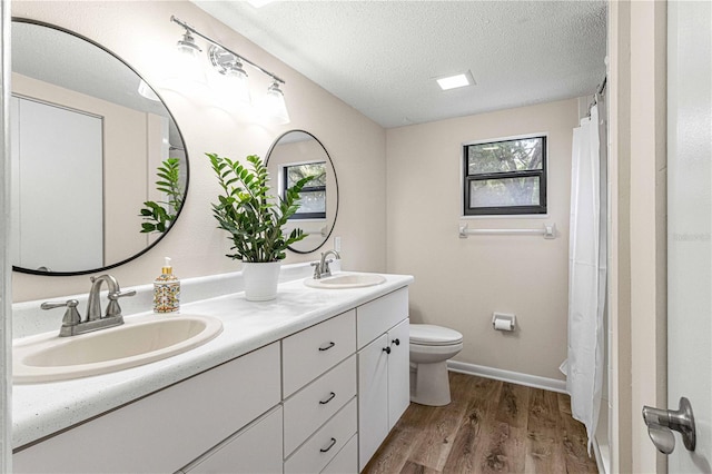 bathroom with toilet, hardwood / wood-style flooring, a textured ceiling, a shower with curtain, and vanity