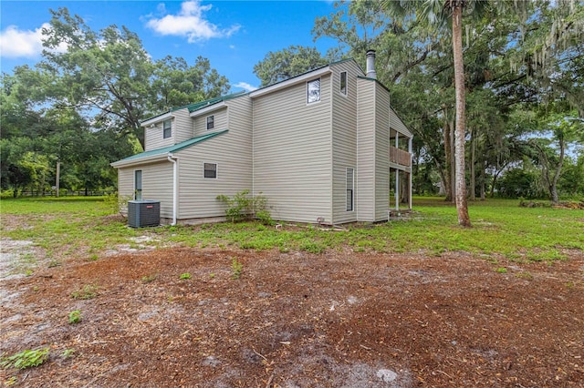 view of side of home with a lawn, central AC unit, and a balcony