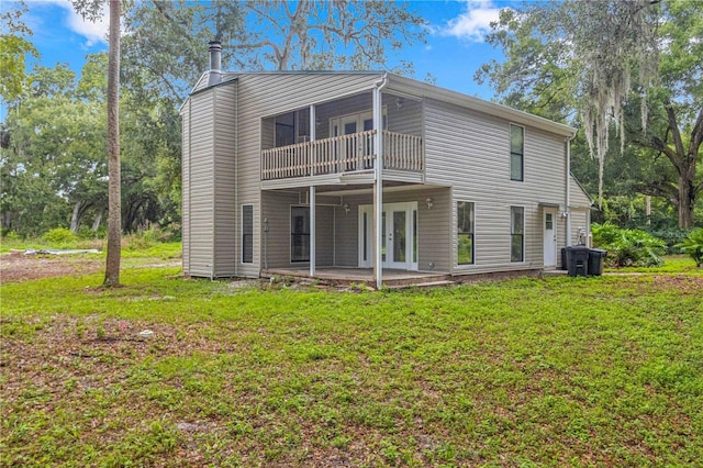 back of property featuring a balcony, a yard, and a patio