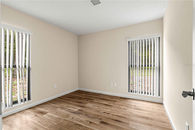 spare room with plenty of natural light and hardwood / wood-style floors