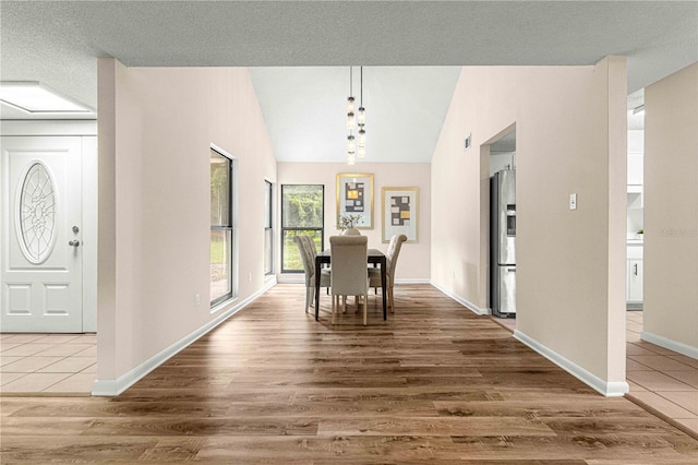 dining space with a textured ceiling, dark hardwood / wood-style flooring, and vaulted ceiling