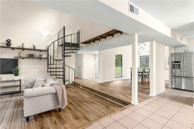 living room featuring a textured ceiling, an inviting chandelier, and light hardwood / wood-style floors